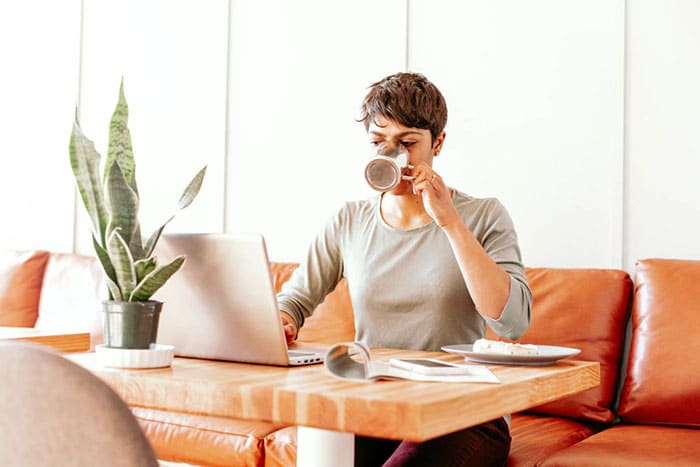 woman drinking coffee while working on her blog