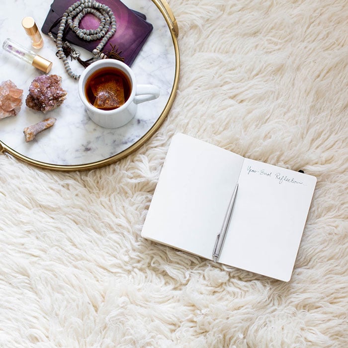 journal with a mug of tea and crystals