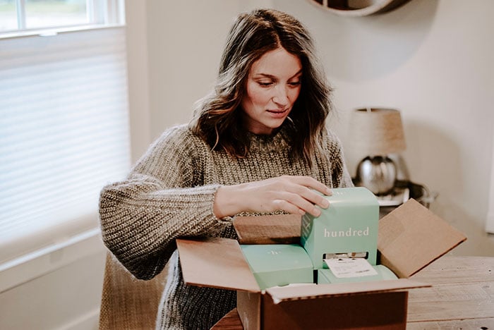 woman opening up Hundred supplements after using discount code