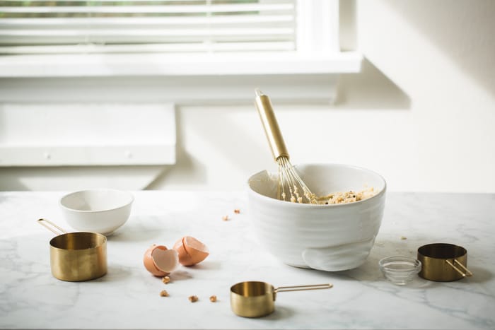 whisk in white bowl mixing up food on kitchen counter