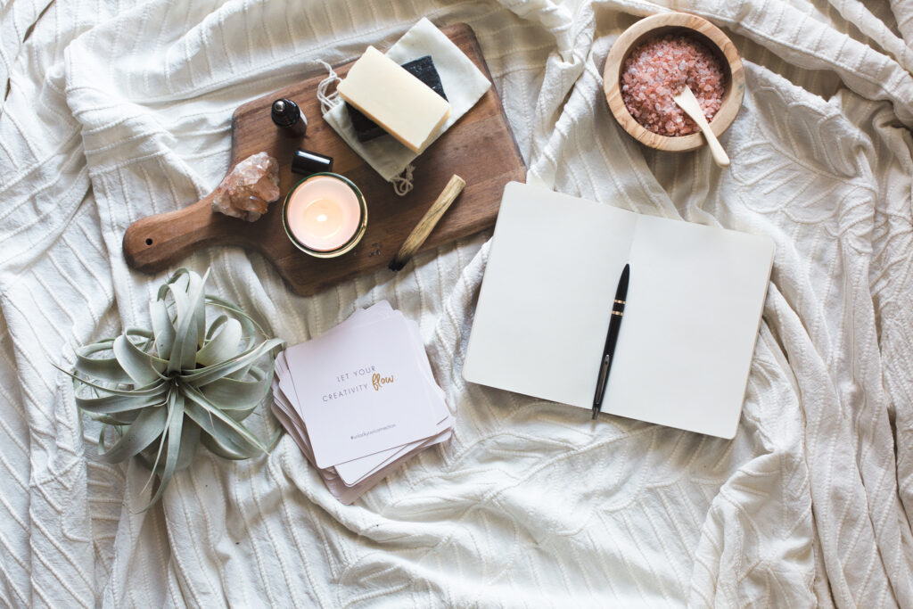 plant with open journal and candle for self care space