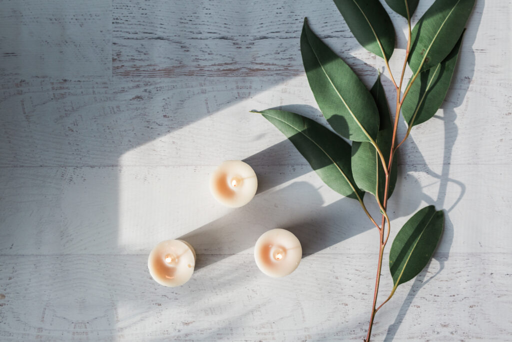 Greenery and candles on white wood background