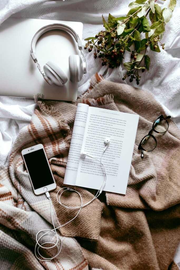 Book and phone on bed with reading glasses