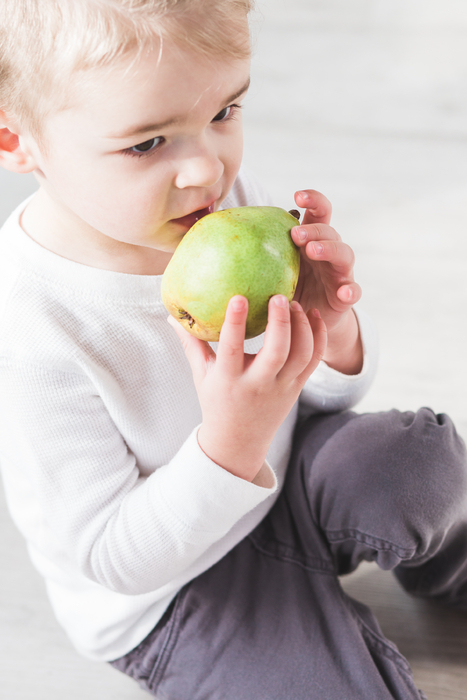 baby biting into green pear for a snack